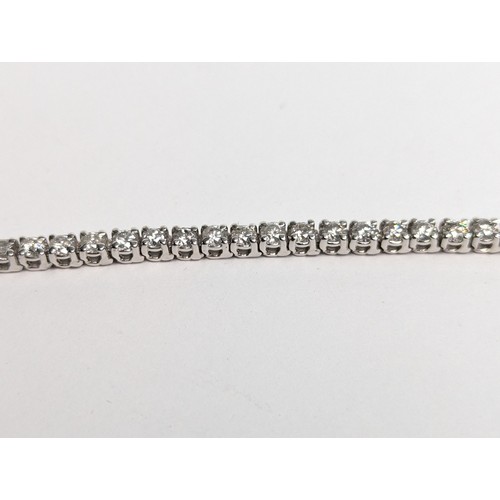 97 - 14ct white gold diamond line bracelet, comprising an articulated line of 56 claw-set brilliant-... 