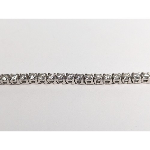 97 - 14ct white gold diamond line bracelet, comprising an articulated line of 56 claw-set brilliant-... 