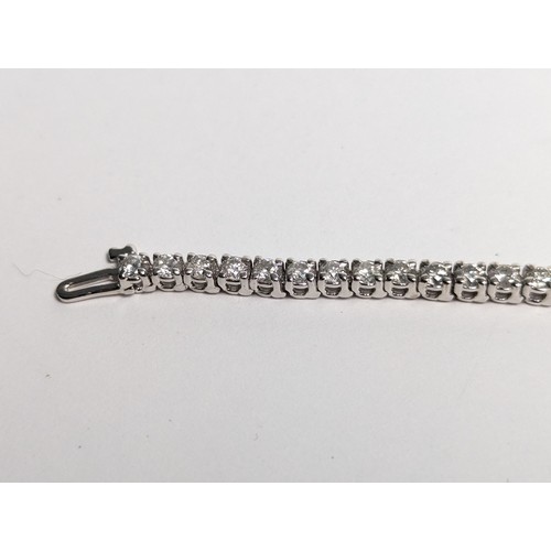 97 - 14ct white gold diamond line bracelet, comprising an articulated line of 56 claw-set brilliant-... 