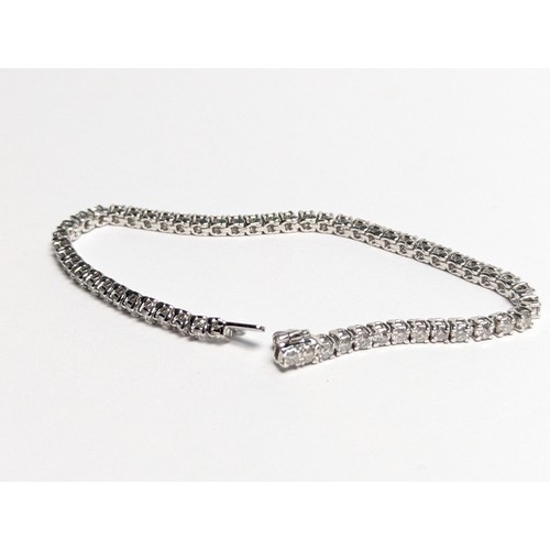 97 - 14ct white gold diamond line bracelet, comprising an articulated line of 56 claw-set brilliant-... 