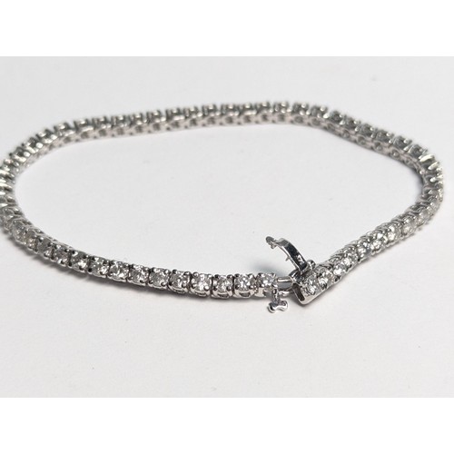 97 - 14ct white gold diamond line bracelet, comprising an articulated line of 56 claw-set brilliant-... 