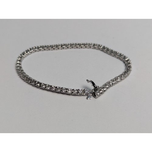 97 - 14ct white gold diamond line bracelet, comprising an articulated line of 56 claw-set brilliant-... 