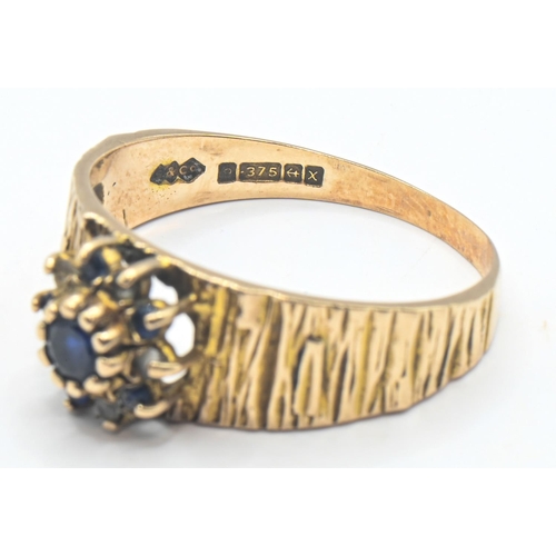 141 - 9ct gold ring with bark style finish and central cluster with sapphire, size R, gross weight 3.39 gr... 