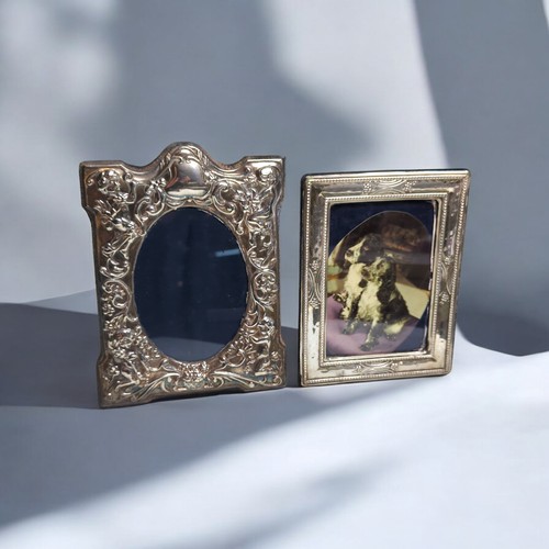 395 - Two silver mounted photo frames, comprising: one with embossed with putti and foliate scrolls, D R &... 