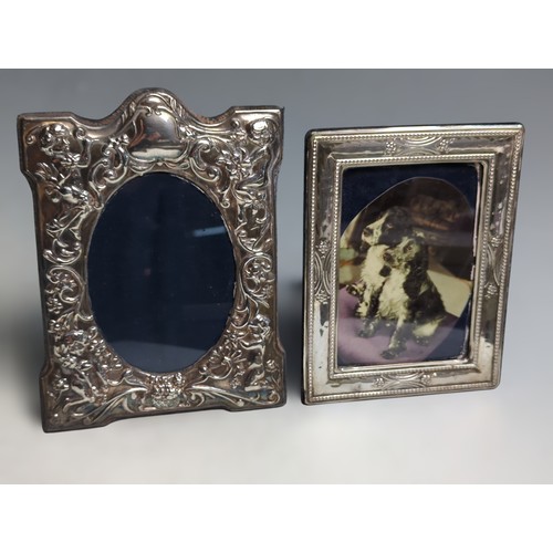 395 - Two silver mounted photo frames, comprising: one with embossed with putti and foliate scrolls, D R &... 