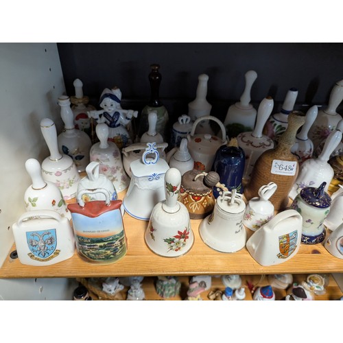 648 - Quantity of assorted ceramic and glass bells over two shelves