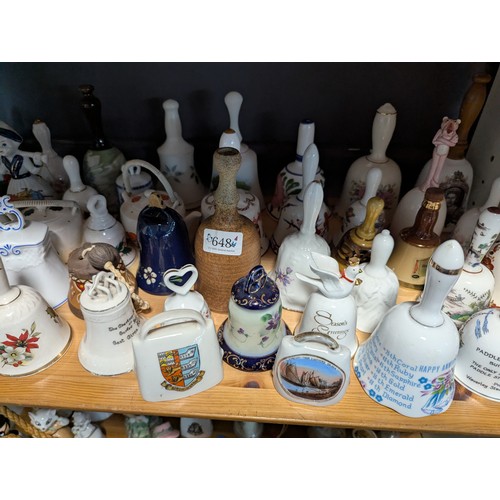 648 - Quantity of assorted ceramic and glass bells over two shelves