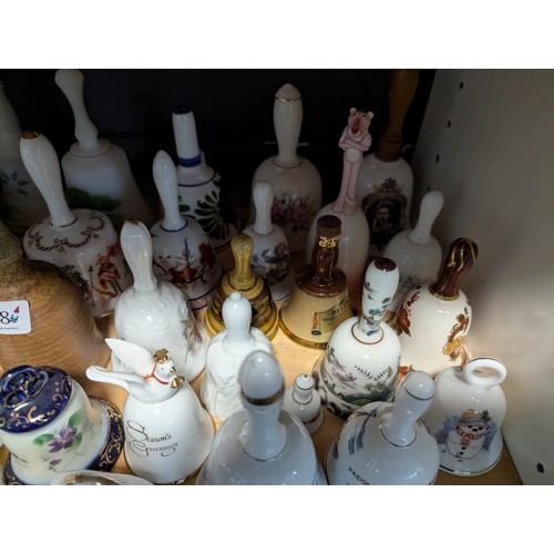 648 - Quantity of assorted ceramic and glass bells over two shelves