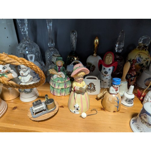 648 - Quantity of assorted ceramic and glass bells over two shelves