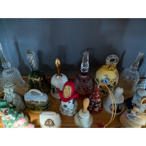 648 - Quantity of assorted ceramic and glass bells over two shelves