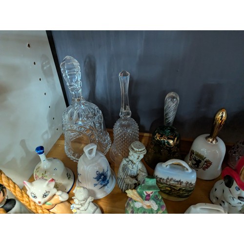 648 - Quantity of assorted ceramic and glass bells over two shelves