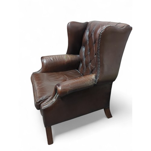 84 - Brown leather Chesterfield-style wingback chair. W81cm D66cm H91cm.