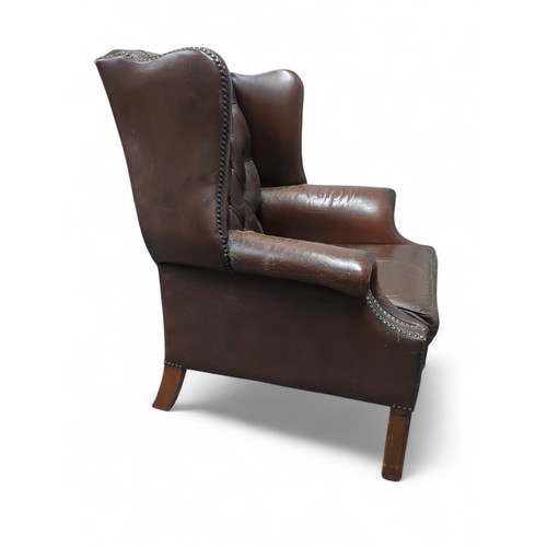 84 - Brown leather Chesterfield-style wingback chair. W81cm D66cm H91cm.