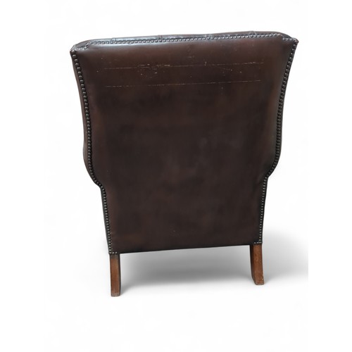 84 - Brown leather Chesterfield-style wingback chair. W81cm D66cm H91cm.