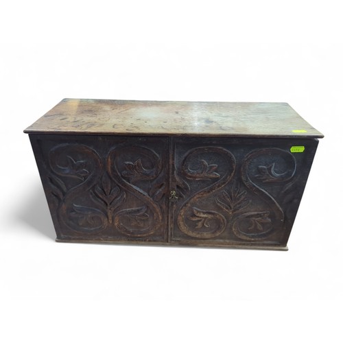 127 - Small carved cabinet with brass latch. W57cm D21cm H30cm.