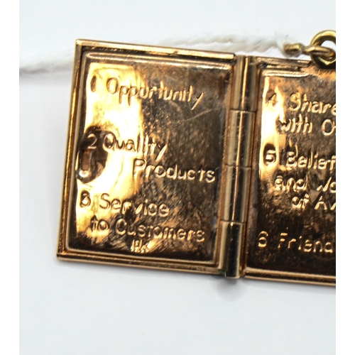 131 - Yellow metal 'The Principles That Guide Avon' book charm, stamped 10K, length including bale 28mm, 7... 