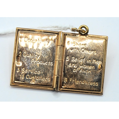 131 - Yellow metal 'The Principles That Guide Avon' book charm, stamped 10K, length including bale 28mm, 7... 