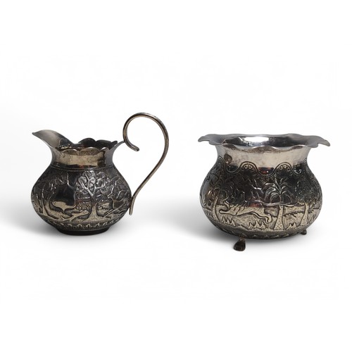 223 - Indian white metal cream jug and sugar bowl, each of different design, with repoussé dec... 