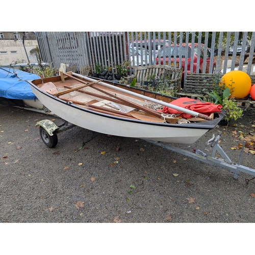 Mirror Dinghy, Class 4149. Built by Bell Woodworking in 1965. Approximately 331cm in length, complete with a single-axle trailer. The boat features a traditional wooden interior and is sold with accessories, including a rudder, mast, and a pair of oars. The boat appears to be in used condition, with areas of damage to gunwale. Inspection in person recommended.
