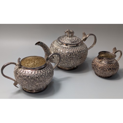 327 - Indian white metal three-piece tea set, the globular bodies with foliate decoration, cobra handles a... 