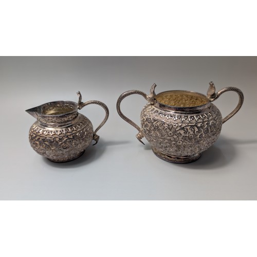 327 - Indian white metal three-piece tea set, the globular bodies with foliate decoration, cobra handles a... 