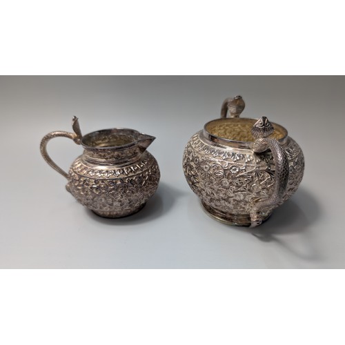 327 - Indian white metal three-piece tea set, the globular bodies with foliate decoration, cobra handles a... 