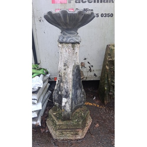 123 - A cast stone garden bird bath, the scalloped bowl on a foliate collar above a tapered hexagonal pede... 