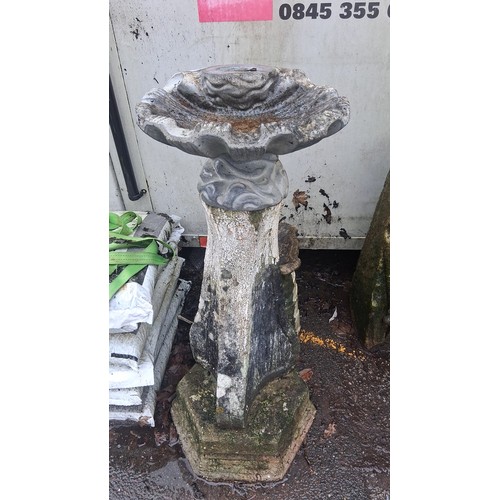 123 - A cast stone garden bird bath, the scalloped bowl on a foliate collar above a tapered hexagonal pede... 