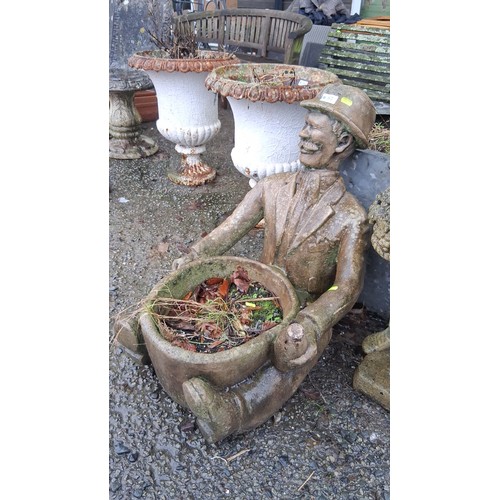 87 - A figural cast stone garden planter modelled as a seated gentleman in hat and suit, holding a circul... 