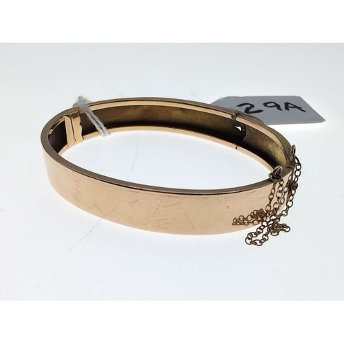 29A - Yellow metal hinged bracelet with loop fastener design, including safety chain, inner width 58mm, 12... 