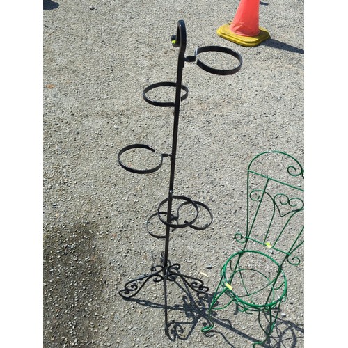 27 - Two metal garden stands: a black multi-ring plant stand on scrolling tripod base, and a green wirewo... 