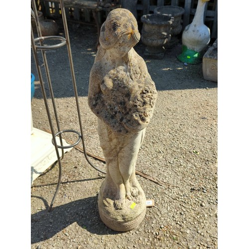 59 - Concrete figure of a young girl cradling a basket of fruit raised on an integral circular plinth wit... 