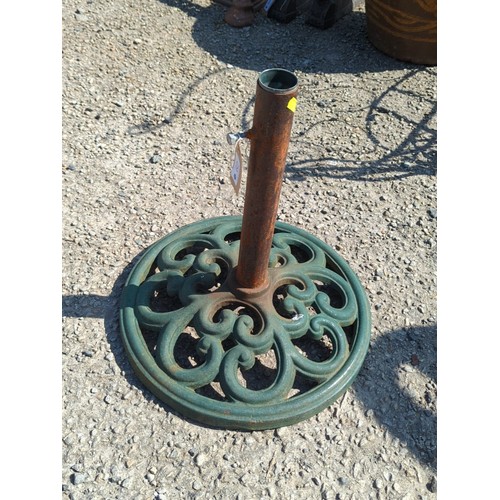 62 - Cast-iron parasol stand with circular pierced scrolling base and central tubular pole receptacle; gr... 