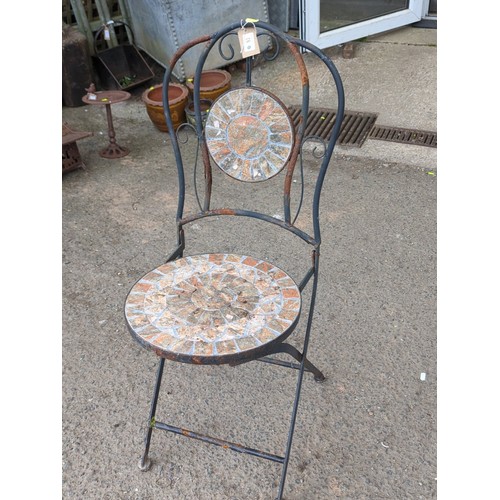 81 - Metal garden chair with scrolling back splat, centred by a circular mosaic roundel; matching circula... 