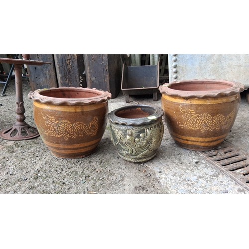 84 - A group of three glazed earthenware jardinieres, comprising two large brown-glazed pots with dragon ... 