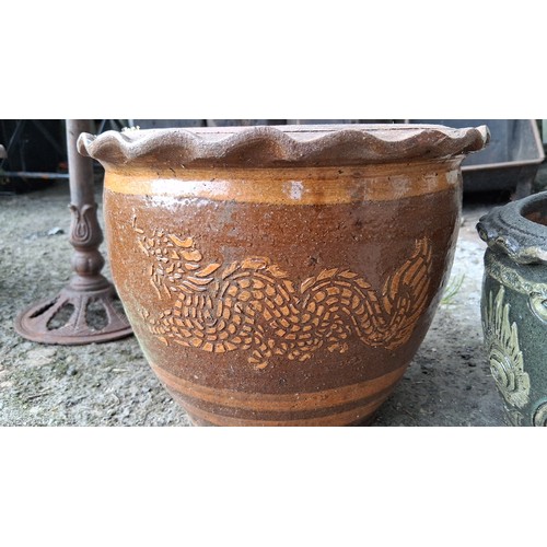 84 - A group of three glazed earthenware jardinieres, comprising two large brown-glazed pots with dragon ... 