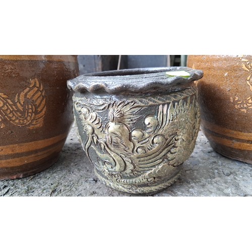 84 - A group of three glazed earthenware jardinieres, comprising two large brown-glazed pots with dragon ... 