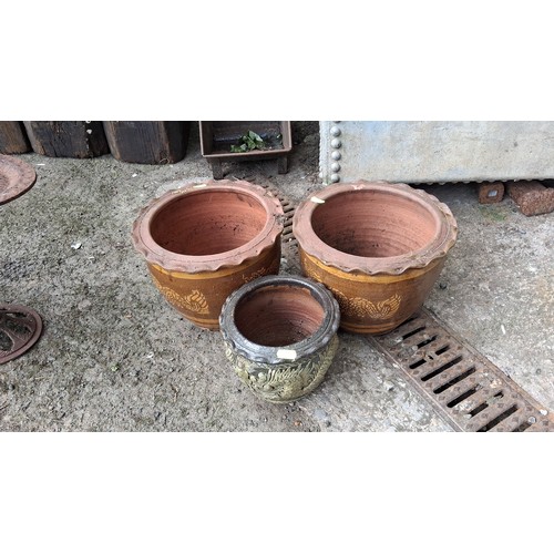 84 - A group of three glazed earthenware jardinieres, comprising two large brown-glazed pots with dragon ... 