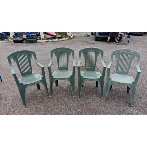 98 - A group of 4 plastic garden armchairs, in green, with slatted backs and curved arms.
