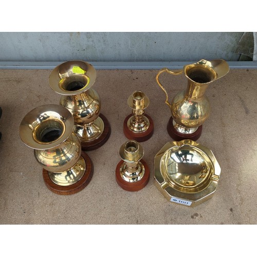 160 - An assortment of brass table wares comprising two bud vases, a ewer, two candlesticks and an octagon... 