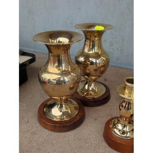 160 - An assortment of brass table wares comprising two bud vases, a ewer, two candlesticks and an octagon... 