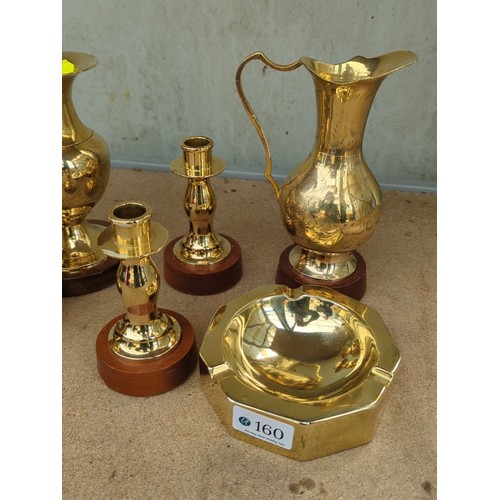 160 - An assortment of brass table wares comprising two bud vases, a ewer, two candlesticks and an octagon... 