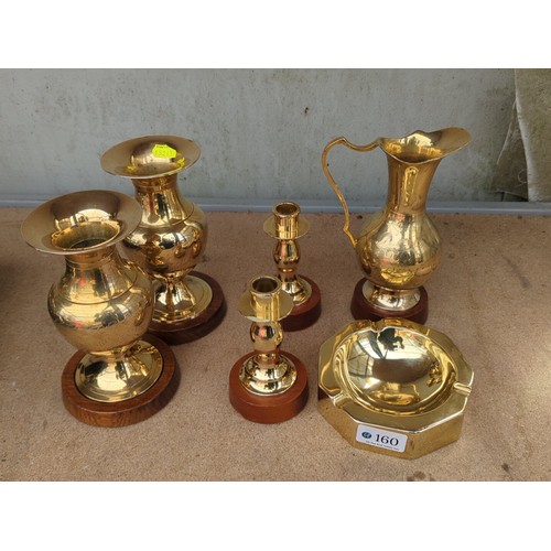 160 - An assortment of brass table wares comprising two bud vases, a ewer, two candlesticks and an octagon... 