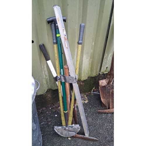 225 - A group of long-handled garden and builder’s tools, including a spirit level, pickaxe head, and vari... 