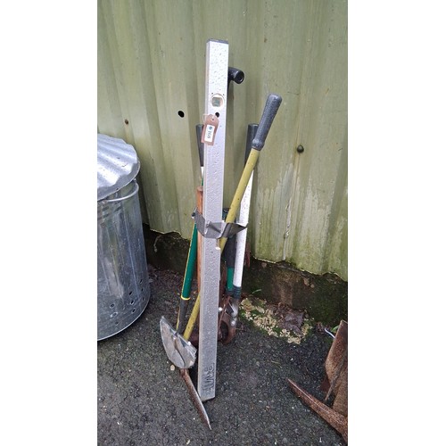 225 - A group of long-handled garden and builder’s tools, including a spirit level, pickaxe head, and vari... 