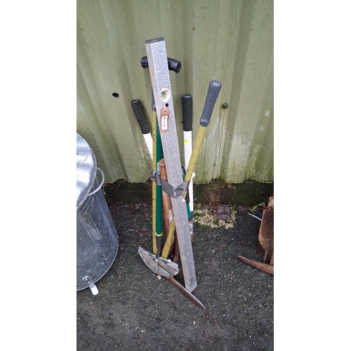 225 - A group of long-handled garden and builder’s tools, including a spirit level, pickaxe head, and vari... 
