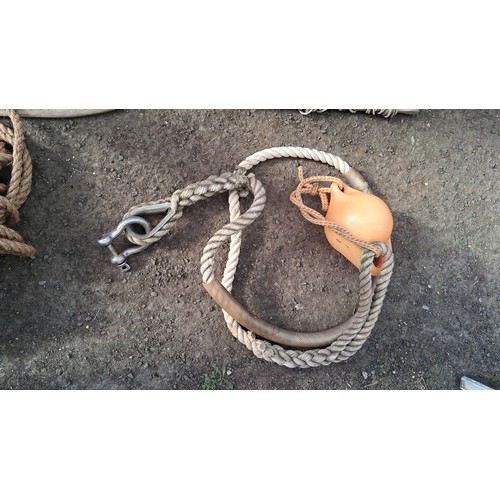 204 - A group of nautical equipment comprising a wooden paddle, coiled rope, and two braided mooring lines... 