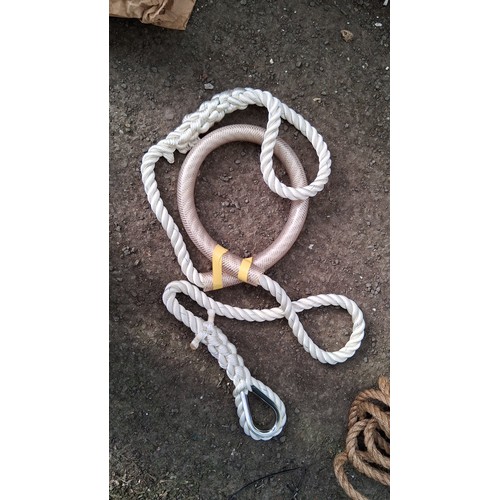 204 - A group of nautical equipment comprising a wooden paddle, coiled rope, and two braided mooring lines... 