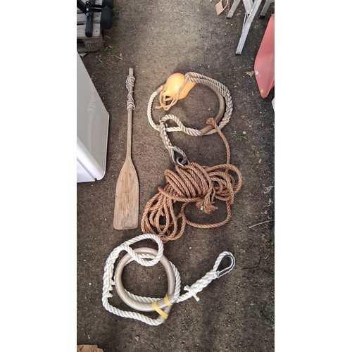 204 - A group of nautical equipment comprising a wooden paddle, coiled rope, and two braided mooring lines... 