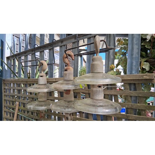 232 - A group of three overhead power-line glass disc insulators, each fitted with a metal cap and hook su... 